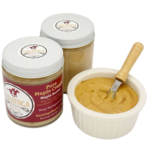 Two jars of pure maple butter with a bowl and butter knife on a white background
